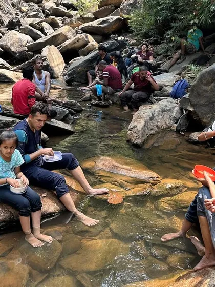 Trekkers enjoying a meal while sitting on the rocks in a stream, a unique and refreshing lunch break.