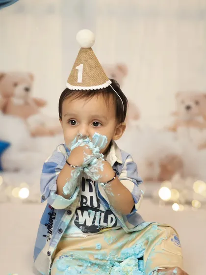Hands full of cake and a look of pure delight. These are the fun, candid moments we love to capture during a cake smash session.