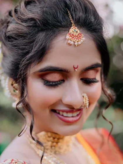 A close-up of the bride's monochromatic makeup look, featuring soft, dewy skin and warm tones on the eyes to complement her yellow and red saree.