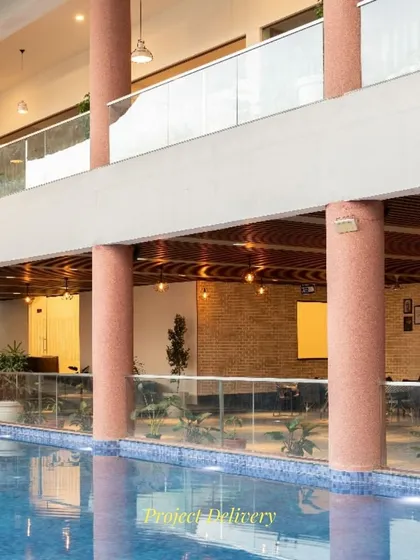A snapshot of the Sona Vistaas clubhouse during its final stages. This view from the mezzanine highlights the interplay of columns, levels, and the swimming pool below, showcasing the project's spatial complexity.