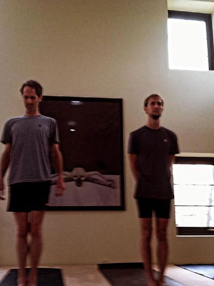 Practitioners standing in Samasthitihi, the foundational pose of equal standing. This moment captures the focus and dedication that are central to the Ashtanga practice.