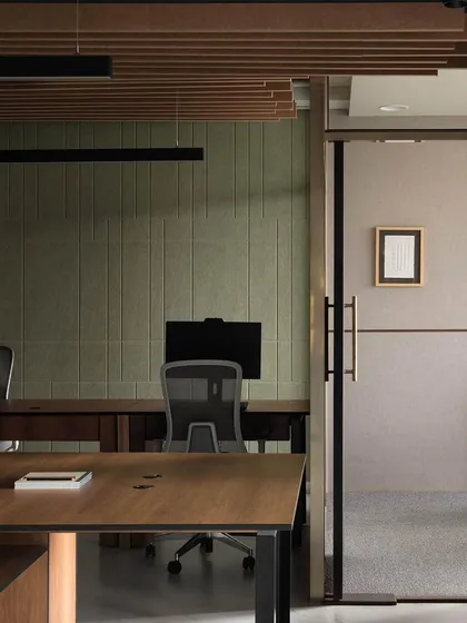 This view of a contemporary office workspace highlights our focus on creating distinct functional zones. A glass partition with black framing separates a private cabin from the open-plan desk area, maintaining a sense of transparency while providing necessary acoustic privacy.
