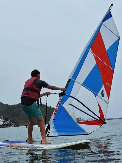 A participant successfully catches the wind in his sail, experiencing the thrill of gliding across the water on a windsurfer.