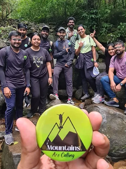 A guide holds up our signature badge with a group of trekkers in the background. This badge is a small souvenir for our participants.
