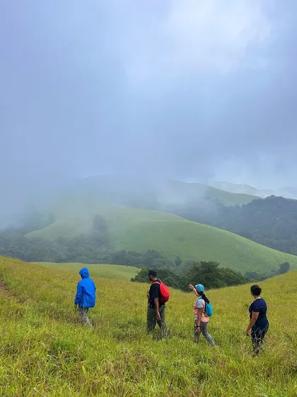 Trekkers walking along the trail in the rolling green hills of Bandaje.