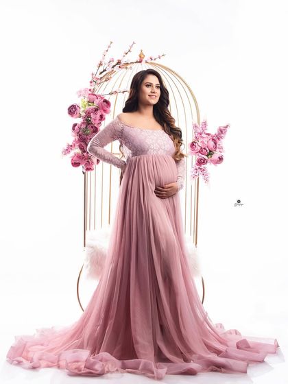 A confident and radiant pose in a pink lace gown, set against the floral birdcage prop. This setup is perfect for creating glamorous and whimsical maternity photos.