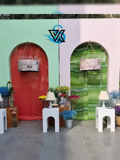 This colorful photo booth was designed for a Haldi function. The backdrop features pastel green and pink arches with contrasting drapes, surrounded by fresh flowers and quirky lamps for a fun and eclectic look.