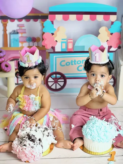 A twin cake smash is double the fun and double the mess. These two one-year-olds are enjoying their individual cakes in a colorful candyland-themed studio setup.