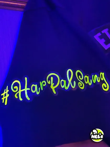 The custom sleeve detail on the bachelor party T-shirt, featuring the wedding hashtag "#HarPalSang" in glowing neon script.
