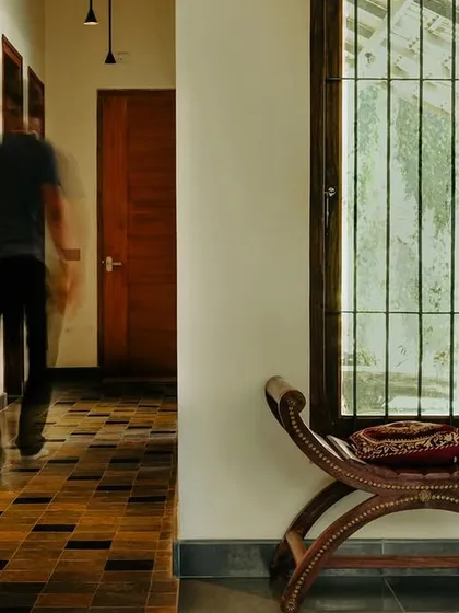 This corridor in our 'Sharanam' project in Coorg captures our love for natural materials. The patterned Kota stone floor provides an earthy foundation, while the play of light and shadow along the wall highlights the custom wooden shelving and natural plaster finish.