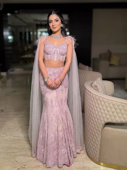 A stunning full-length shot of the mermaid-style gown with feather details. The soft glam makeup is the perfect complement to this high-fashion, statement-making look.