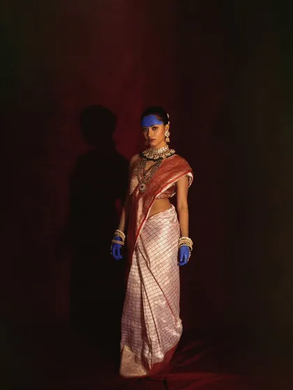 A full-length shot from our conceptual desi series. The traditional saree is contrasted with bold blue paint on the model's face and hands, creating a striking and surreal visual.