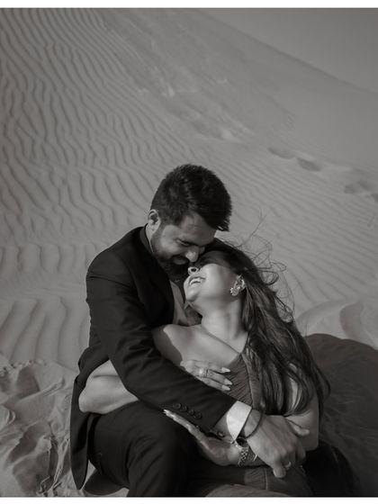 An intimate black and white portrait of a couple in the Dubai desert. The close framing and their joyful expressions create a powerful sense of connection and happiness.