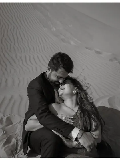 An intimate black and white portrait of a couple in the Dubai desert. The close framing and their joyful expressions create a powerful sense of connection and happiness.