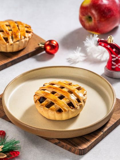 Miniature apple pies with a lattice crust, presented on wooden boards with Christmas decorations for a cozy, festive feel.