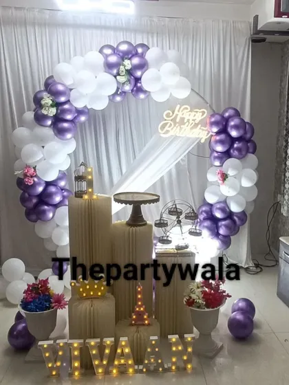 A chic and modern ring decoration with purple and white balloons. The white curtain backdrop and simple props create a very clean and elegant look.