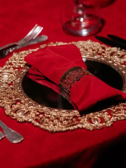 An example of our detailed tablescaping for a destination wedding. This setting features a rich red theme with ornate gold charger plates and deep red velvet napkins, creating a look of pure luxury.