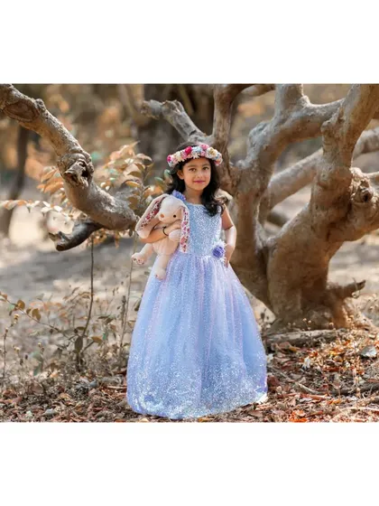 A full-length portrait of Brishka in her sparkling blue gown, standing in a forest setting. This wide shot captures the enchanting, fairytale quality of her seventh birthday photoshoot.