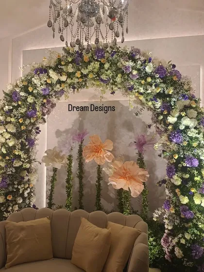 For this baby shower, I designed a whimsical floral arch using a mix of purple and white flowers, with delicate paper flowers adding a touch of playfulness. The elegant sofa provides a comfortable and beautiful spot for the mom-to-be.