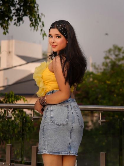 A bright yellow top paired with a classic denim skirt is a go-to combination for a cheerful summer outfit. The ruffled detail on the top adds a fun, feminine touch.