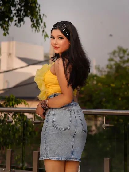 A bright yellow top paired with a classic denim skirt is a go-to combination for a cheerful summer outfit. The ruffled detail on the top adds a fun, feminine touch.