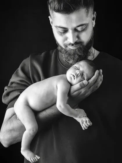 A touching black and white photo of a father cradling his newborn baby in his arms.