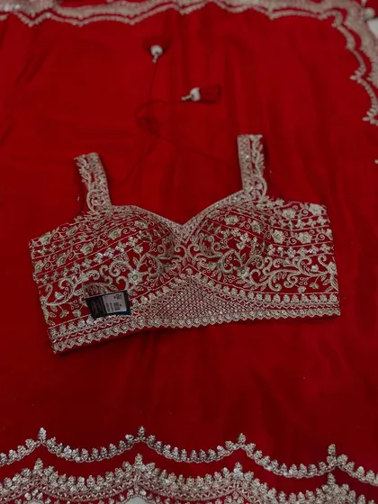 The classic combination of red and silver is always a winner. This is a close-up of our Chinon party wear set, showcasing the intricate embroidery on the blouse and the matching scalloped border on the saree.