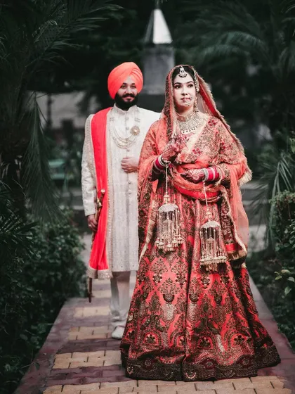 A classic portrait of a Sikh bride and groom in a lush garden setting.