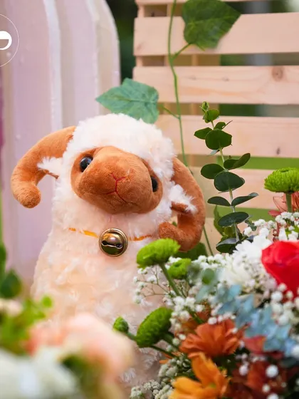 An adorable stuffed sheep peeking out from a floral arrangement, adding a touch of whimsy to the decor.
