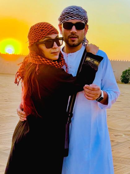 A picture with my husband during the desert safari. He's wearing a traditional white kandura, and I'm in a black abaya, embracing the local culture.