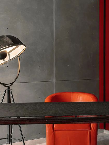 A detail from the 'House of the Hanging Gardens', where a bold red wall contrasts with a raw concrete finish and an industrial-style floor lamp.