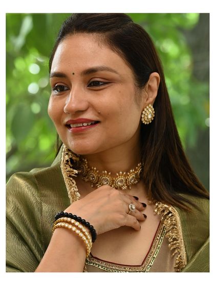A client enjoying a private jewelry viewing at our Gurgaon studio. She is trying on a beautiful kundan choker set, experiencing the feel and look of the piece firsthand.