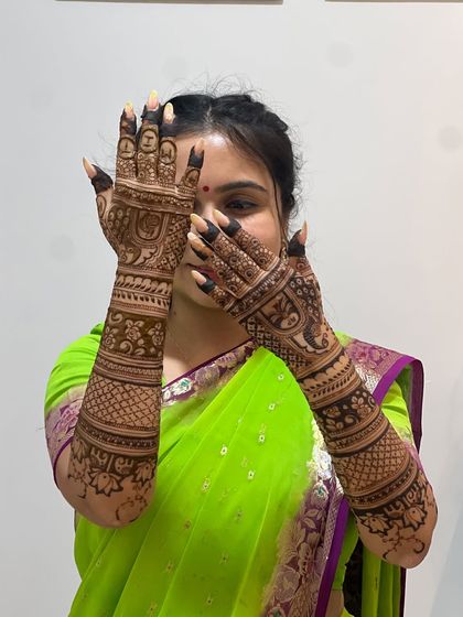 A classic peek-a-boo pose, with the bride's face framed by her beautifully hennaed hands.