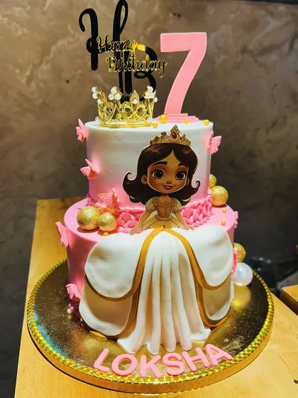 A full view of the two-tier princess cake for Loksha, showcasing the flowing fondant gown and elegant gold crown.
