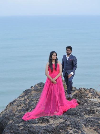 A classic pre-wedding portrait on a cliff overlooking the sea. The flowing pink gown with a long train is a perfect choice for such a dramatic location.