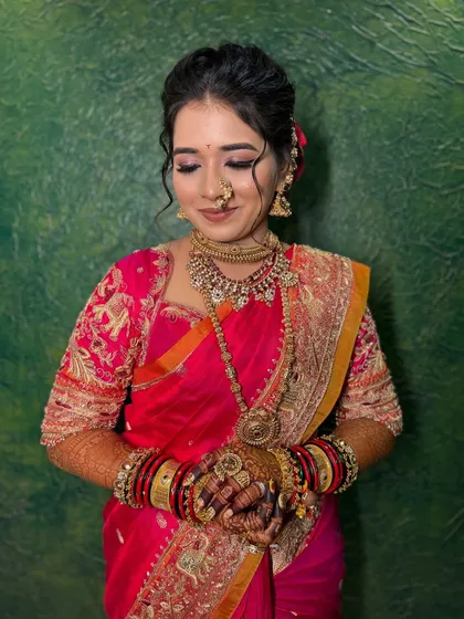 A beautiful portrait of a bride in her pink wedding saree, adorned with heavy gold jewellery.