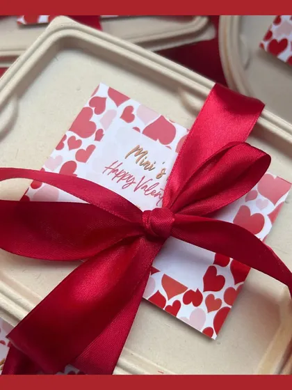 A close-up of the Valentine's Day hamper packaging, complete with a red ribbon and a personalized note. It's all about making the experience special.