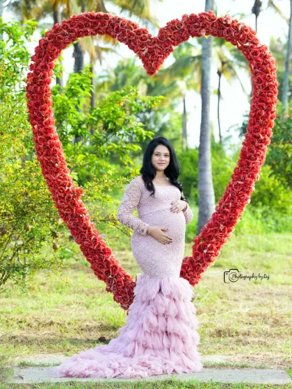 A beautiful portrait of a mother-to-be in a pink lace gown, framed by our red floral heart prop.
