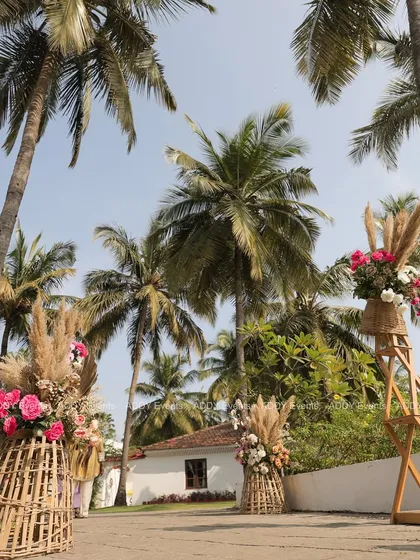 Rustic floral arrangements in large wicker baskets line the pathway, creating a beautiful and natural aisle for a destination-style wedding.
