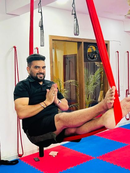 A moment of gratitude and a happy smile. This student enjoys the feeling of being supported by the hammock in a simple seated pose, ready for the next challenge.