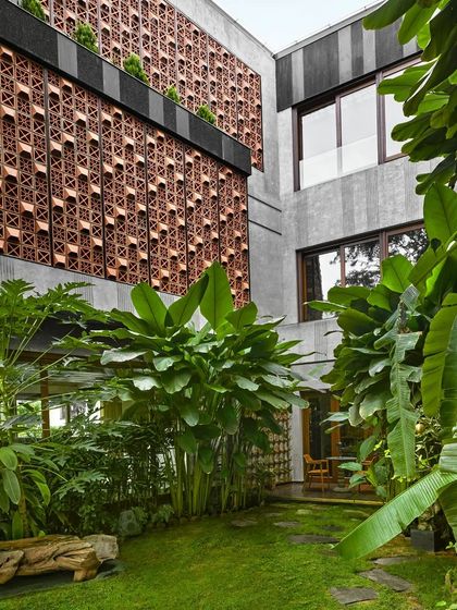 The inner courtyard of Project 58, where a custom terracotta screen provides privacy and texture, seen through a lush garden that penetrates the heart of the home.