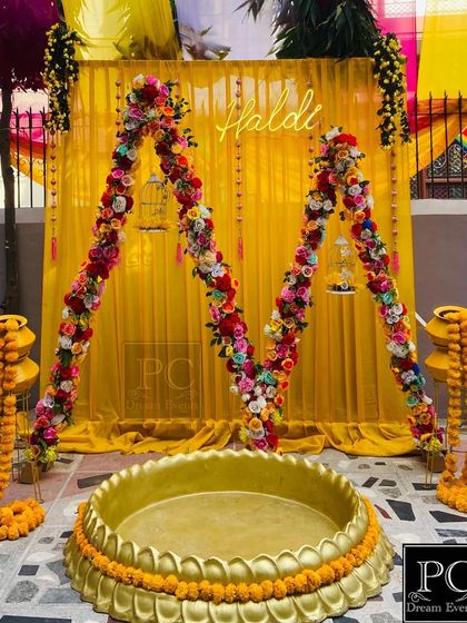 The full setup for the personalized Haldi ceremony, complete with a neon sign, floral arches, and traditional matkas decorated with marigolds.