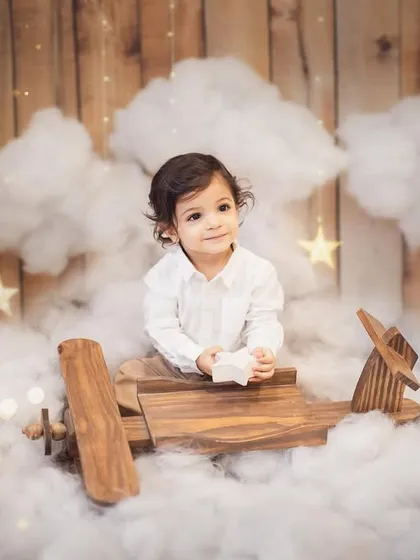 A duplicate of image 1, this shot captures the little pilot holding a star, adding a touch of magic to his first birthday photoshoot. Every detail in the setup is crafted to build a beautiful story.