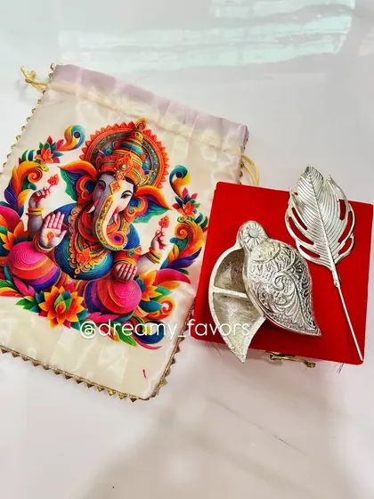 This is one of my favorite return gifts for Ganesh Chaturthi. It features an elegant silver-coated Tilak Dibbi box paired with a vibrant Ganpati print potli bag. It's a beautiful blend of tradition and artistry that your guests will cherish.