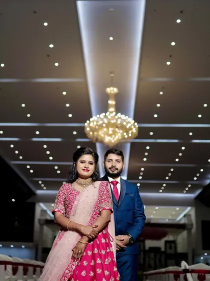 A beautiful portrait of the couple at their wedding reception. The grand chandelier and the elegant hall decor create a sophisticated and celebratory atmosphere.