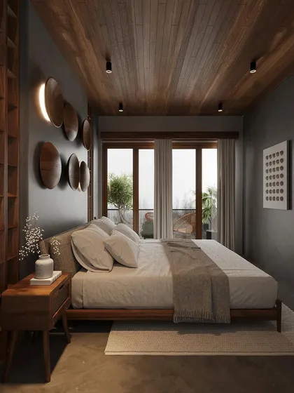 This bedroom design uses a palette of dark, earthy tones to create a cozy and intimate retreat. A wood-planked ceiling and custom wooden wall art add warmth and texture, while the large glass doors open to a private balcony, blending the indoor and outdoor environments.