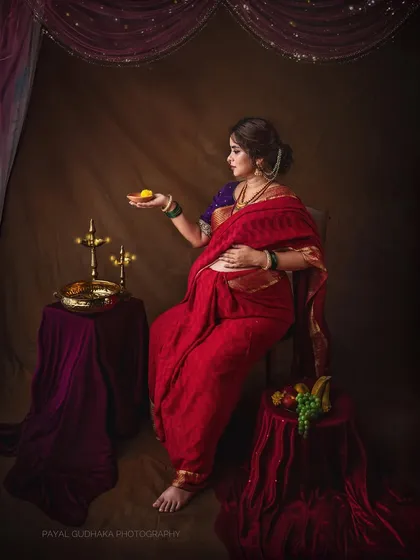 In this pose, the mother-to-be holds a single laddoo, a gesture that adds a touch of narrative and tradition to the portrait, reminiscent of offerings in classical art.