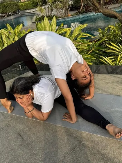 Partner yoga is a beautiful dance of trust, balance, and support. Here, two students work together to achieve a deep backbend and split, demonstrating incredible flexibility and connection.