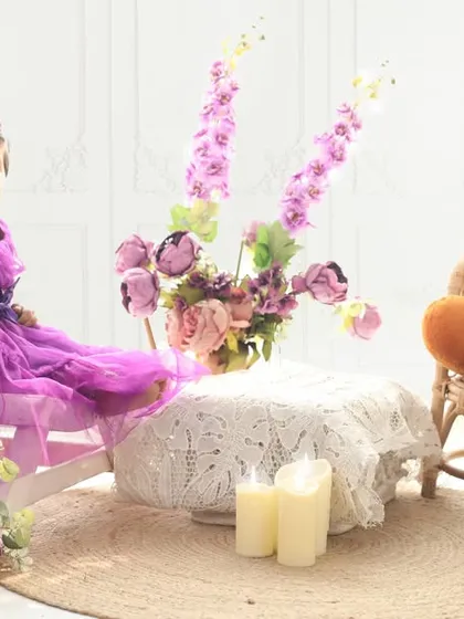 A tiny tea party for a little princess and her teddy bear. This elegant setup with soft purple and white tones, flowers, and a miniature table creates a whimsical scene for a one-year-old's portrait session.