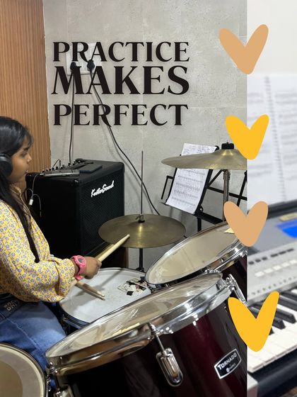 A student focused during her drum lesson, right below our motto: "Practice Makes Perfect." We believe in this simple truth.